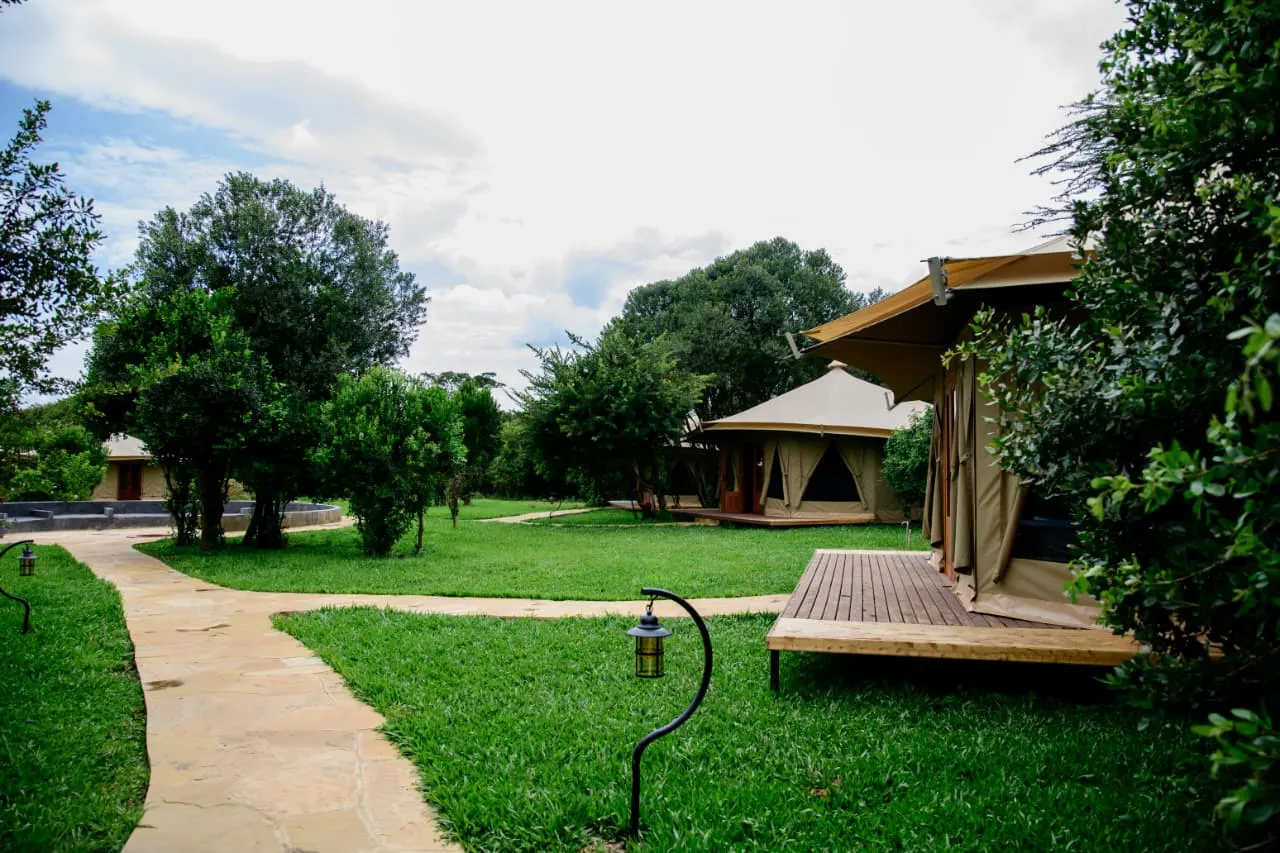 Batian tented suites with timber decks set along a flagstone path through the village garden